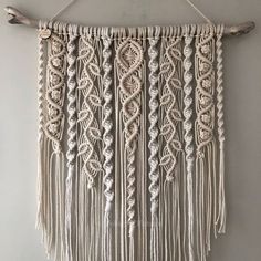 a macrame wall hanging on a white wall