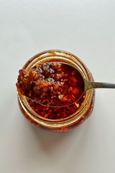 a spoon full of food sitting in a jar on a white counter top with the lid open