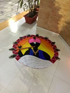 a colorful mat on the floor in front of a potted plant with a woman's face painted on it