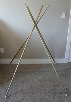 a metal tripod is standing in front of a white wall and carpeted floor