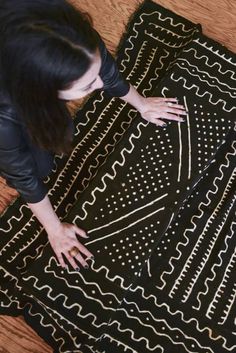 a woman standing on top of a wooden floor next to a black and white rug