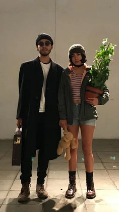 a man and woman standing next to each other holding stuffed animals in front of a white wall