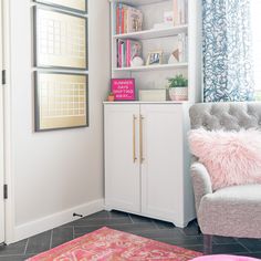 a living room with a chair, bookshelf and pink rug on the floor