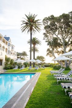 an empty swimming pool surrounded by lawn chairs and umbrellas