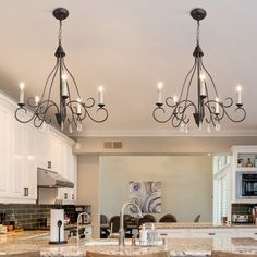 a kitchen with an island and chandelier hanging from it's ceiling lights