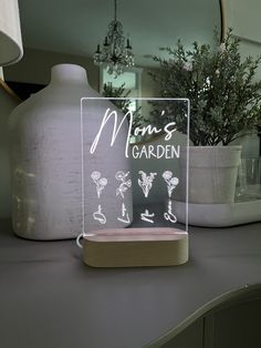 a glass sign sitting on top of a table next to a vase and potted plant