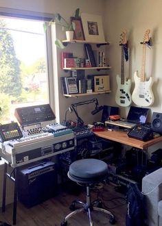 a room filled with musical equipment and guitar's on the wall next to a window