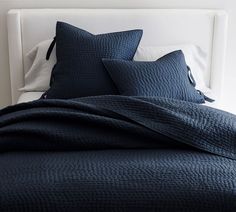 a bed with blue sheets and pillows on it's headboard in a bedroom