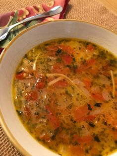 a white bowl filled with soup on top of a table next to a fork and spoon