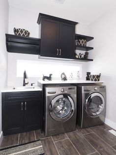 a washer and dryer in a room with dark wood floors, black cabinets, and white walls