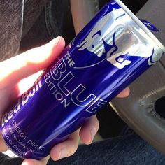 a person is holding a can of soda in their hand while sitting on a car seat