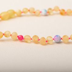 a beaded necklace with glass beads and colorful beads on the end, sitting on a white surface