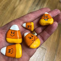 four handmade pumpkins with faces on them sitting in the palm of someone's hand