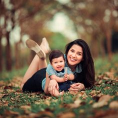 a woman laying on the ground holding a baby in her lap and smiling at the camera