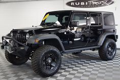 a black jeep is parked in a large room with a checkered floor and white walls