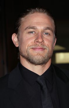 a man with a beard wearing a black suit and tie