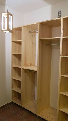 an empty room with some wooden shelves and a light hanging from the ceiling in front of it