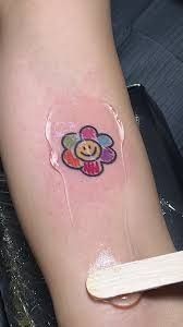 a person with a smiley face tattoo on their arm