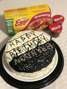 a birthday cake sitting on top of a white plate next to an egg carton