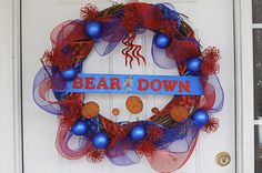 a wreath that says bear down hanging on a door with blue and red decorations around it