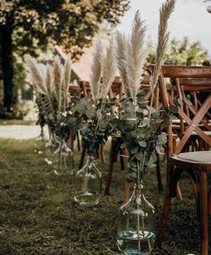 there are many vases with plants in them on the grass near some chairs and tables