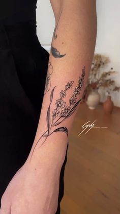 a woman with a tattoo on her arm holding a flower in one hand and an arrow in the other