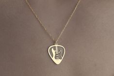 a woman wearing a necklace with a guitar pick on it