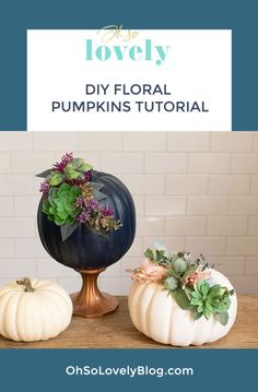 three white pumpkins sitting on top of a wooden table next to a blue vase