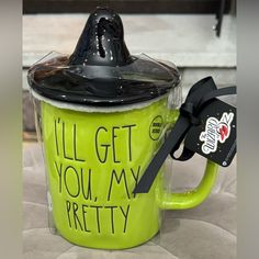 a green coffee cup with a black lid and handle that says, i'll'll get you my pretty