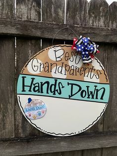 a sign that says best grandparents hands down on a wooden fence with a red, white and blue bow