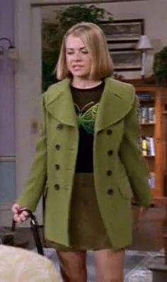 a woman in a green coat holding a black bag