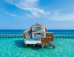 an over water villa on stilts in the middle of clear blue water with a dock leading to it