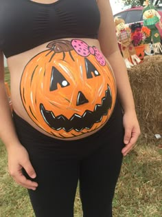 a pregnant woman with her belly painted like a pumpkin