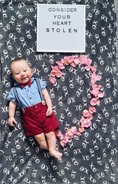 a baby laying on top of a blanket next to a sign that says consider your heart stolen