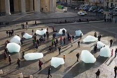 many people are walking around with large icebergs in the middle of an open courtyard