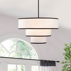 a modern chandelier hanging from the ceiling in a living room with white walls and windows