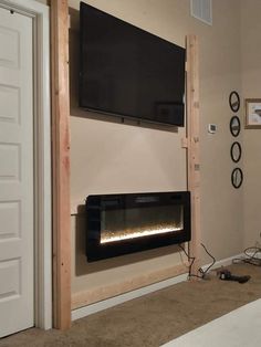 a room with a television mounted on the wall and a fire place in front of it