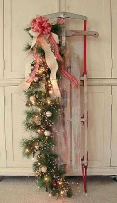 a wooden sled with christmas decorations and lights on the bottom is sitting in front of a door