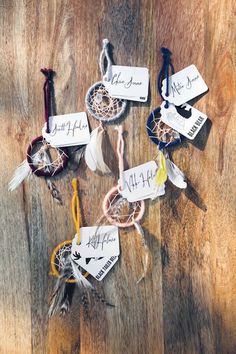 several small dream catchers with name tags attached to them on a wooden table top