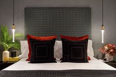 a bed with two black and red pillows sitting on it's headboard next to a potted plant