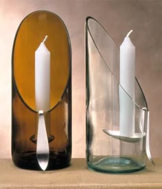 two glass vases with candles in them sitting on a table next to each other