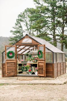 a small greenhouse with wreaths on the doors and windows is shown in front of some trees