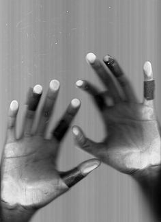 two hands reaching up towards each other with their fingers extended out to the side, in black and white