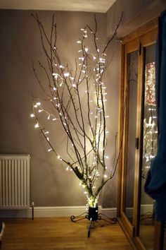 a lighted tree in the corner of a room with a radiator next to it