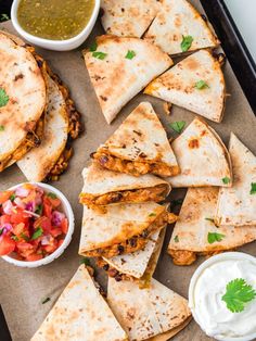 quesadillas on a tray with salsa and sour cream