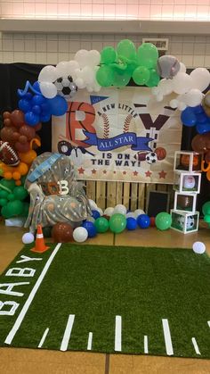 an indoor sports themed birthday party with balloons and footballs on the field in front of it