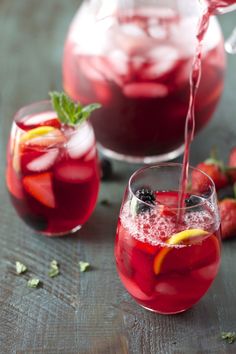 two glasses filled with red liquid and strawberries