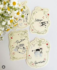 four coasters with animals and names on them next to some daisies in a vase