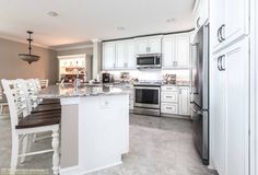 a large kitchen with white cabinets and an island in the middle of it, along with stainless steel appliances