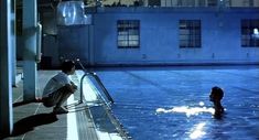 a man sitting on the edge of a swimming pool next to a fire hydrant